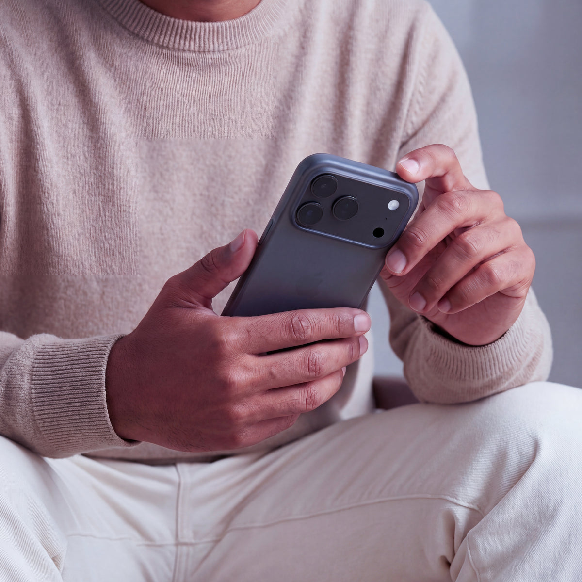 iPhone en coque ORIGINAL Noir fumé tenu à deux mains, vue du dos