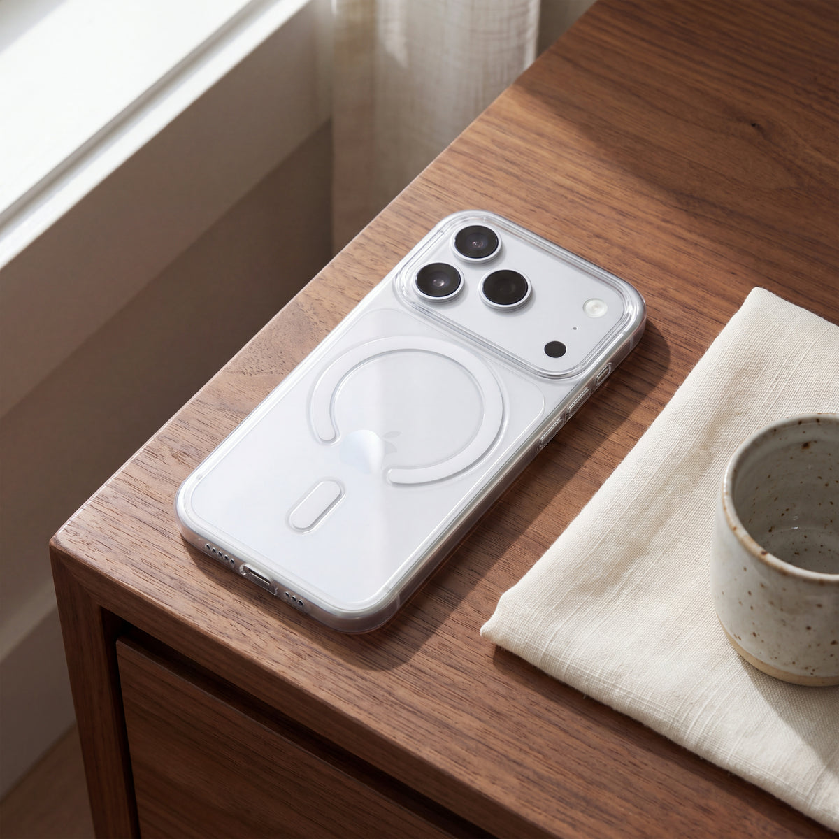 Coque PHANTOM S transparente MagSafe pour iPhone 18 Pro et Pro Max sur un téléphone Argent posé sur une table en bois