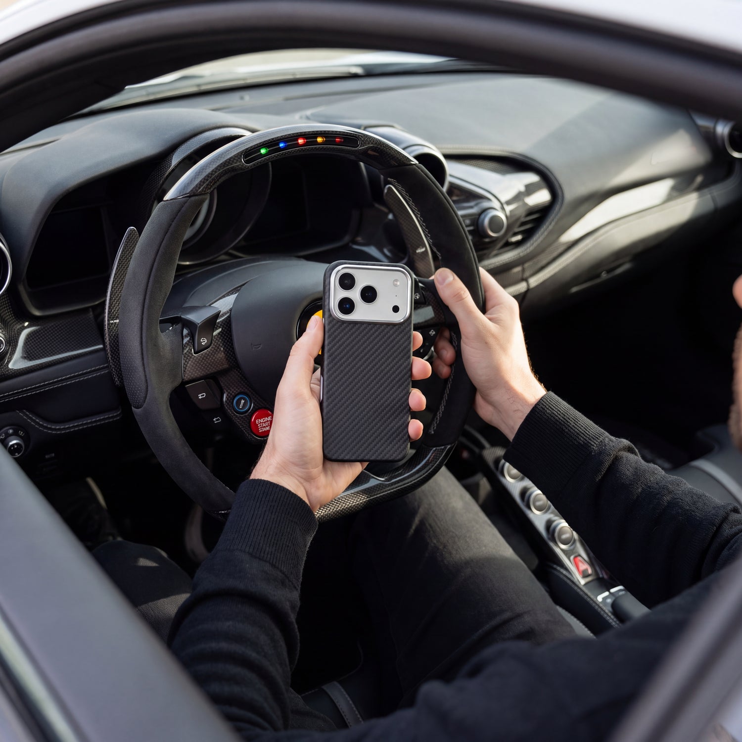 Coque CARBON tenue en main dans l'habitacle d'une supercar, son tissage répondant au carbone du volant et de la planche de bord