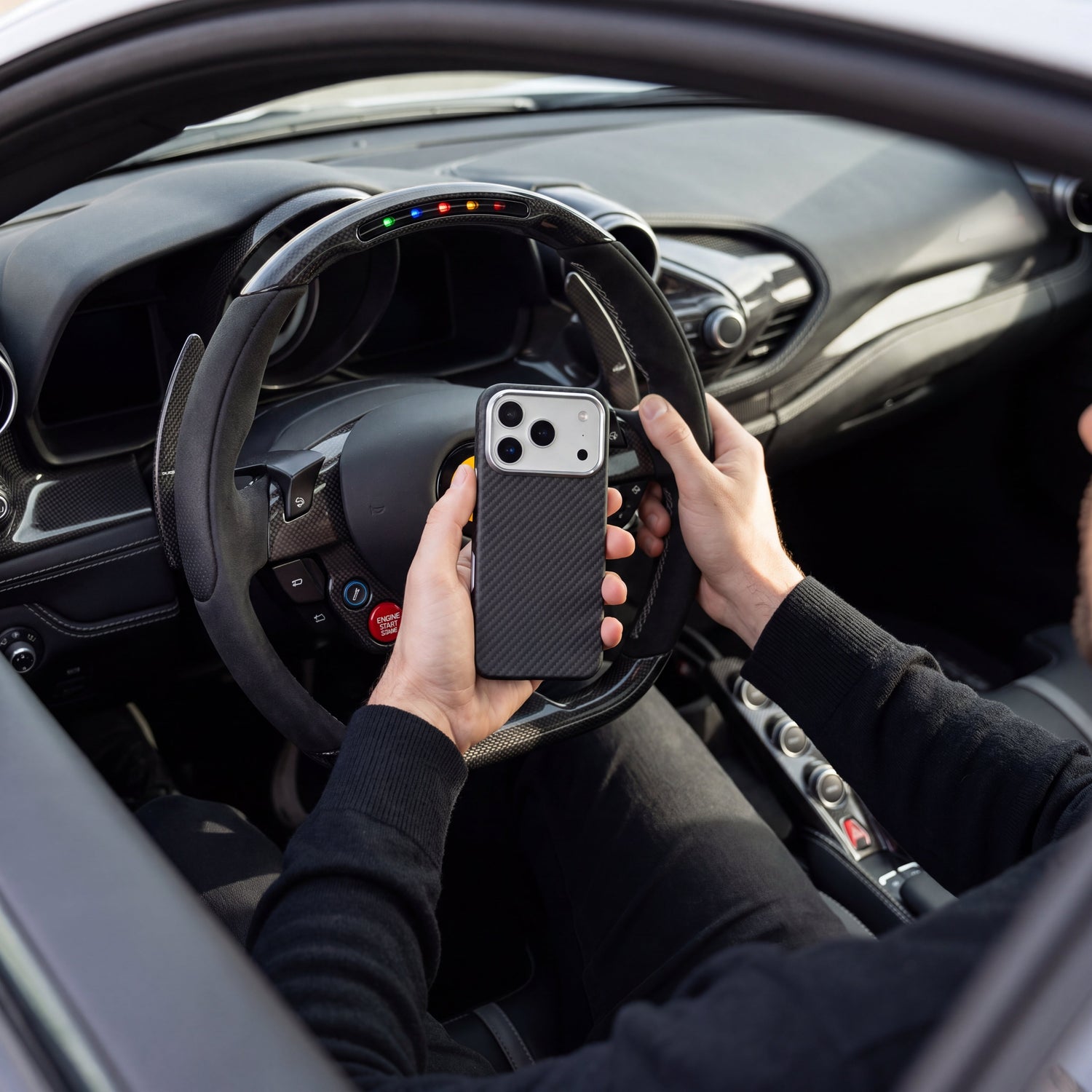 Coque CARBON tenue en main dans l'habitacle d'une supercar, son tissage répondant au carbone du volant et de la planche de bord