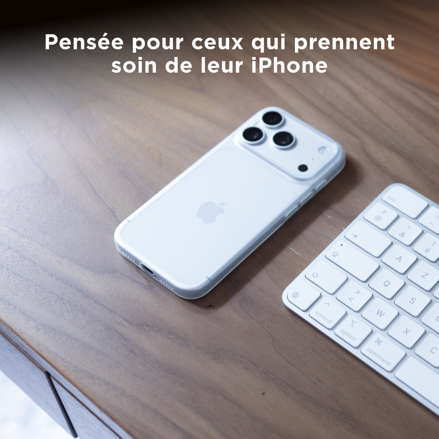 iPhone 18 Pro avec coque PHANTOM transparente posé sur un bureau en bois à côté d'un clavier Apple