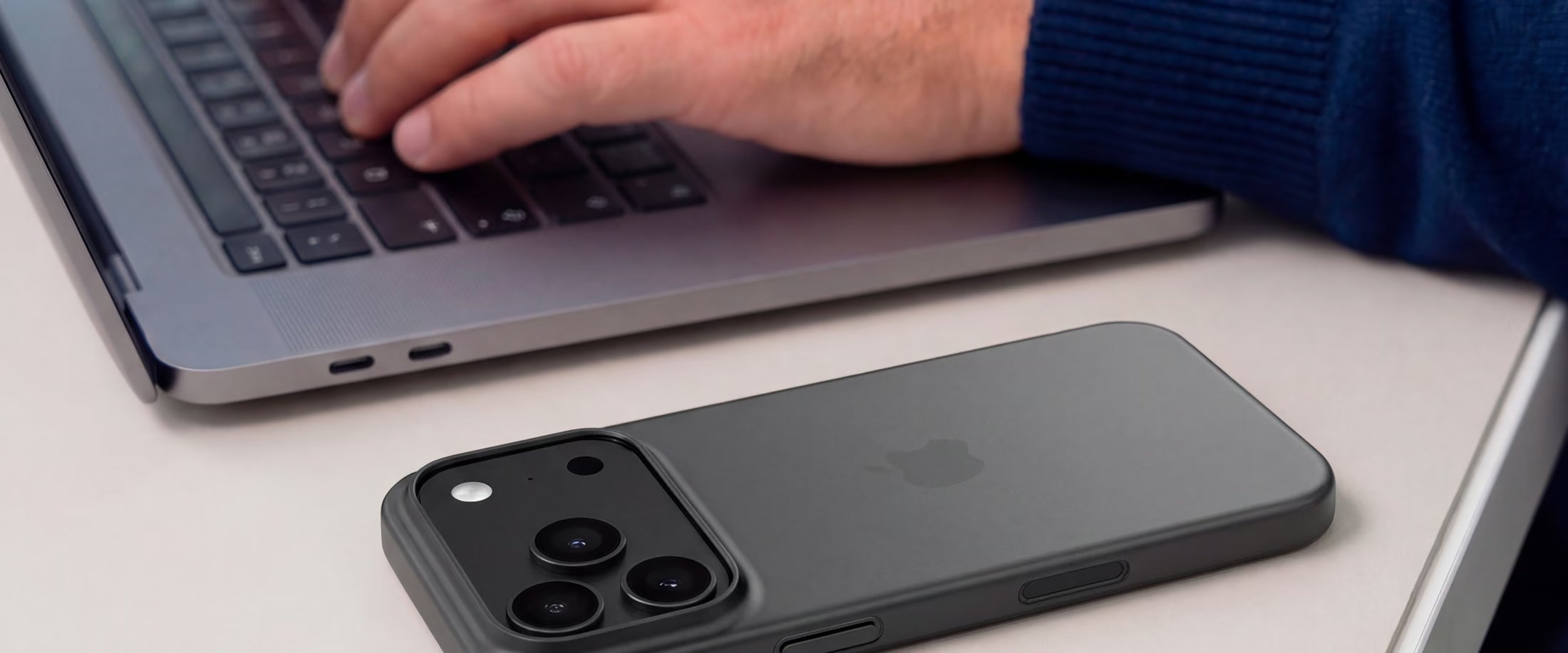 iPhone dans une coque ORIGINAL Noir fumé posé à côté d'un ordinateur portable